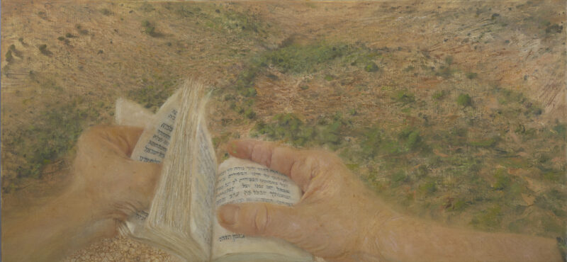 Hands holding prayer book in foreground with Galilee landscape in background